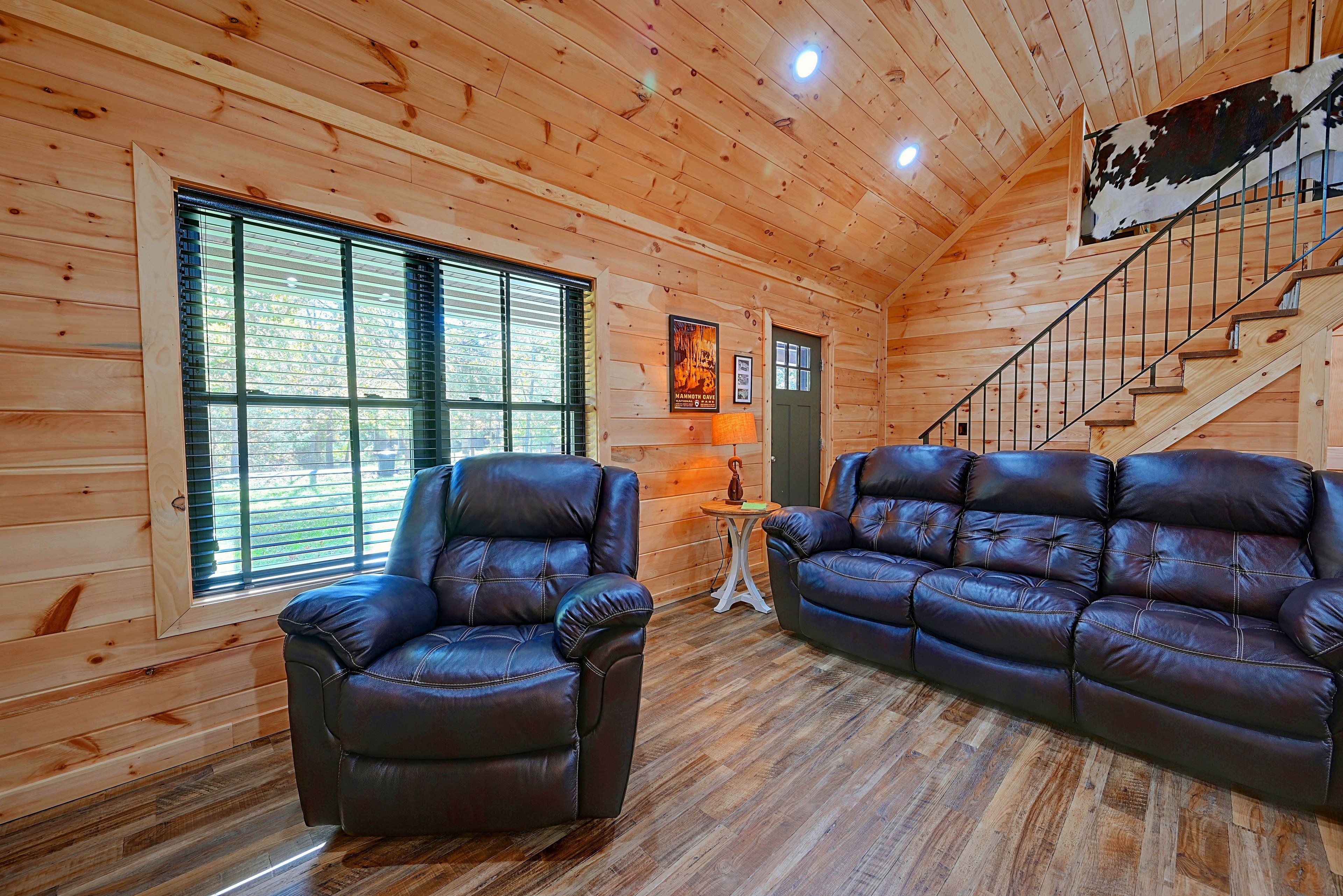 Un interior de madera con un sofá, un sillón y una escalera.