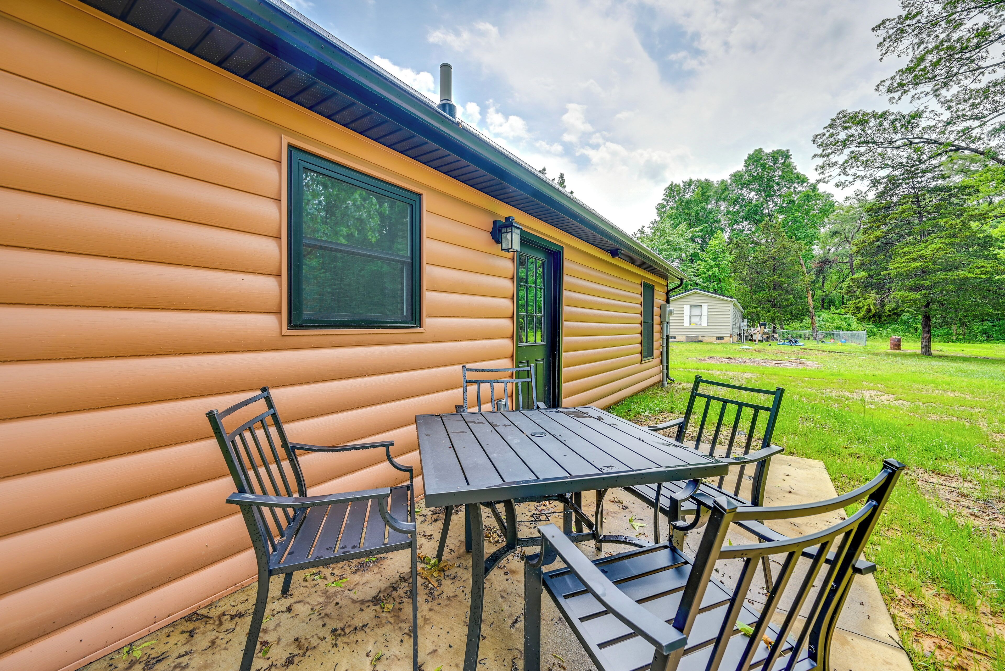 A log cabin with a patio area featuring a table and chairs.