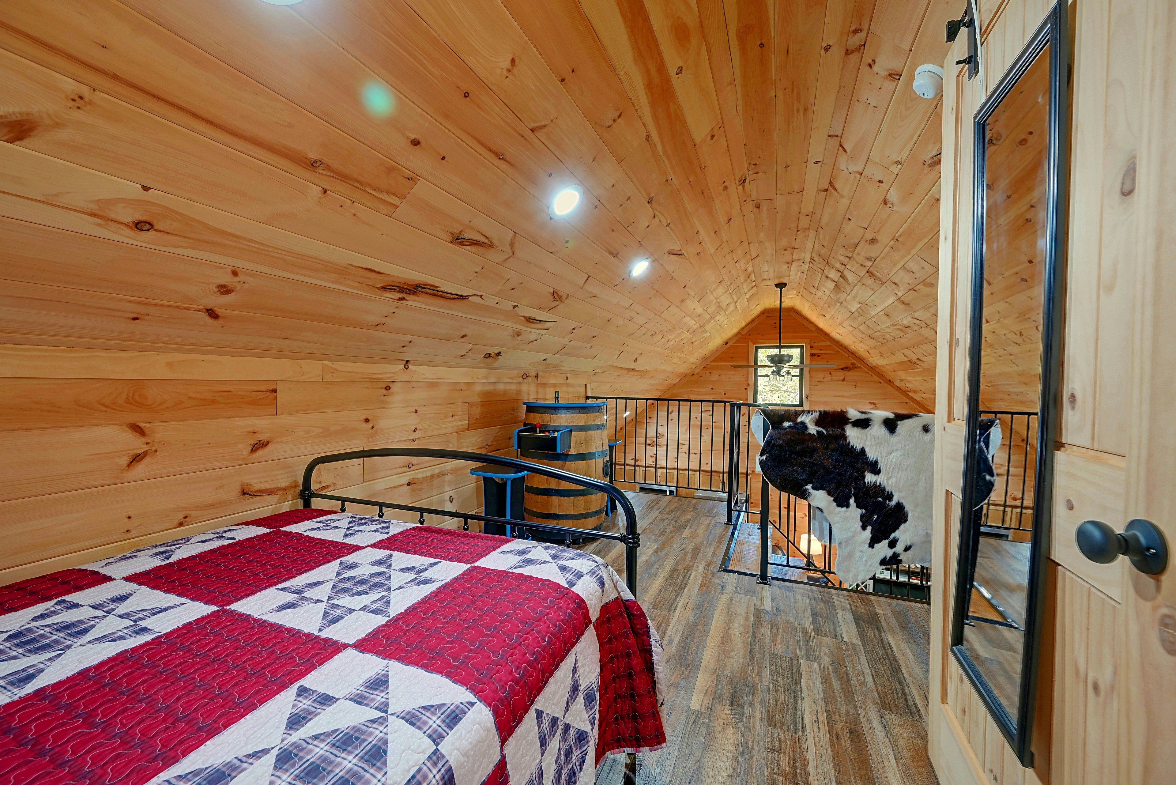 A wooden cabin bedroom with a bed, a small table, and a cow's head decoration.