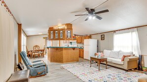 A spacious living area with a sofa, a blue recliner, a wooden kitchen island, and a ceiling fan. - 13 Mi to Okc: Edmond Home w/ Pool Access! (Edmond)
