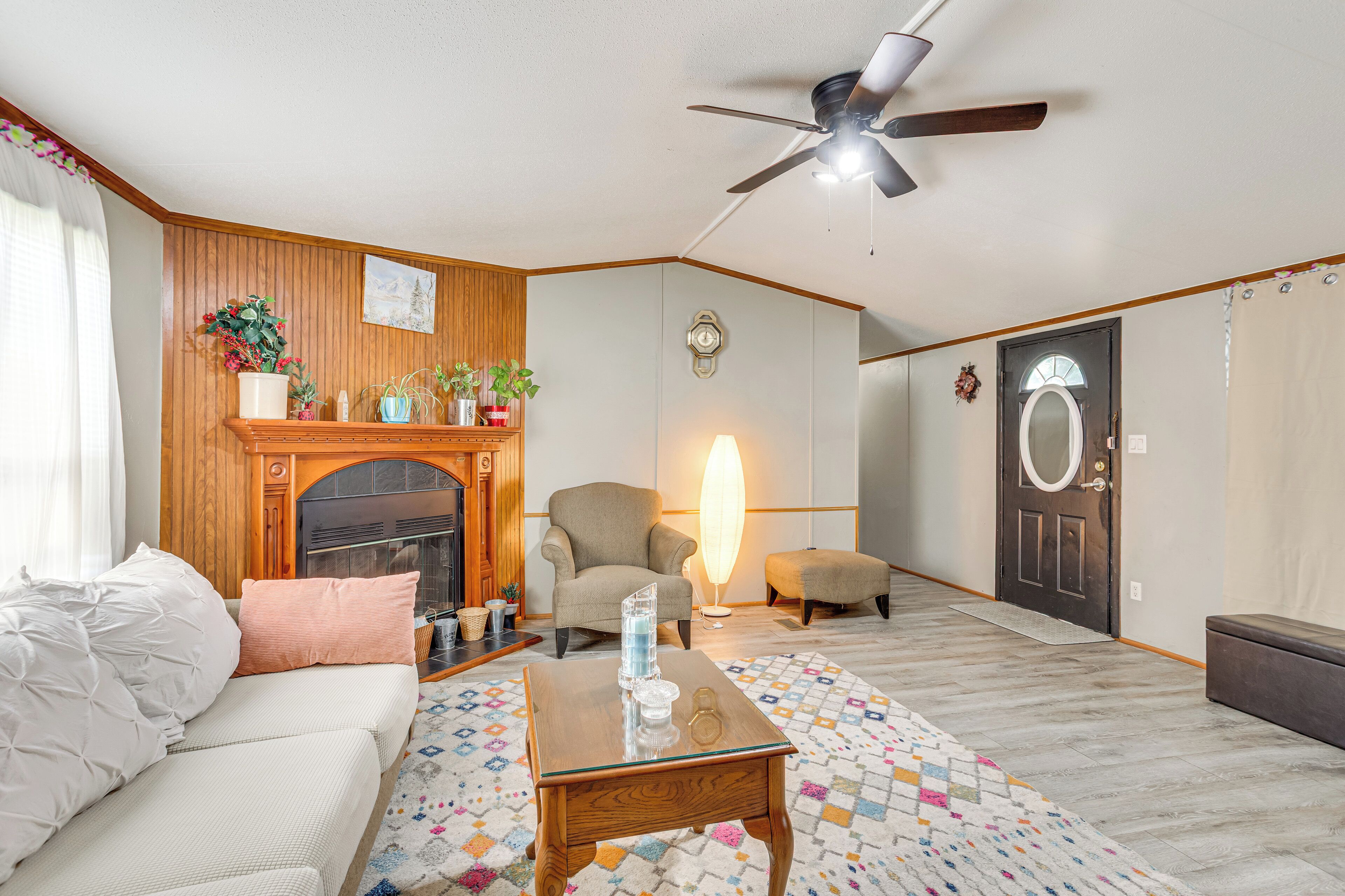 A living room with a sofa, armchair, coffee table, fireplace, and a ceiling fan.
