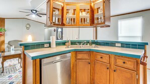 A kitchen with wooden cabinets, a dishwasher, and a countertop with a teal backsplash. - 13 Mi to Okc: Edmond Home w/ Pool Access! (Edmond)