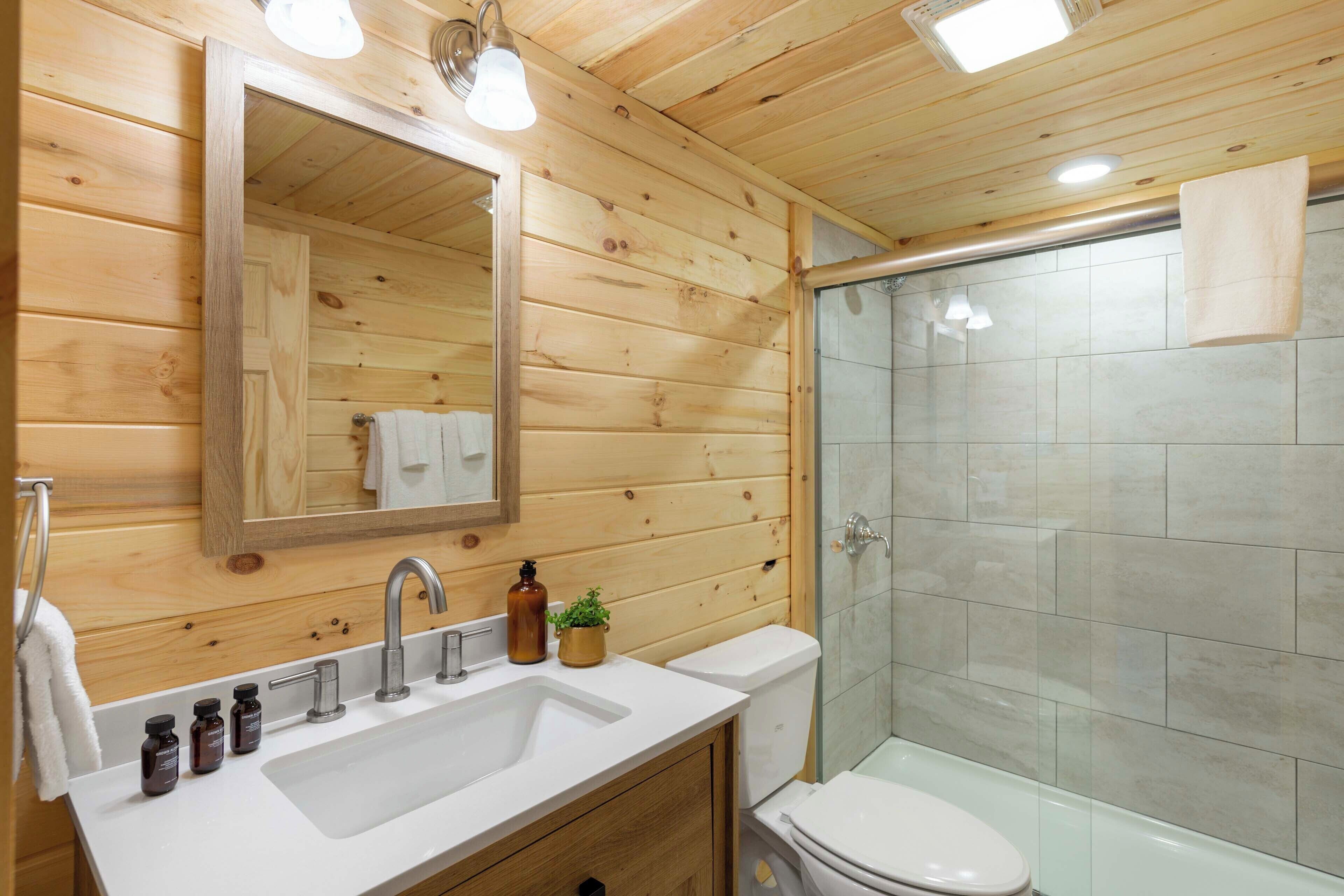 Ein Badezimmer einer Holzhütte mit Waschbecken, Spiegel und Toilette.