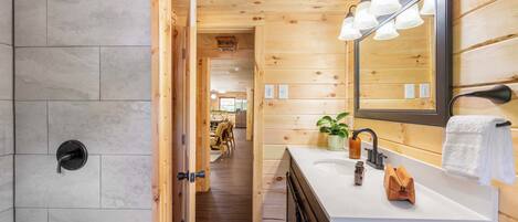 Interior de madera con baño que incluye ducha, lavamanos y espejo.