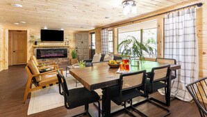 A wooden interior with a dining table, chairs, a flat-screen TV, and a fireplace. - 2 Mi to Dtwn: Spacious Gatlinburg Home w/ Hot Tub! (Gatlinburg)