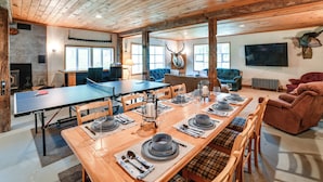 A spacious dining area with a long wooden table set for a meal, surrounded by wooden chairs.