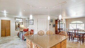 A spacious kitchen with a granite countertop, wooden cabinets, and pendant lighting.