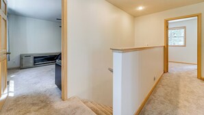 Ein sauberer, gut beleuchteter Flur mit Teppichstufen, die zu einem Zimmer mit Fenster führen.