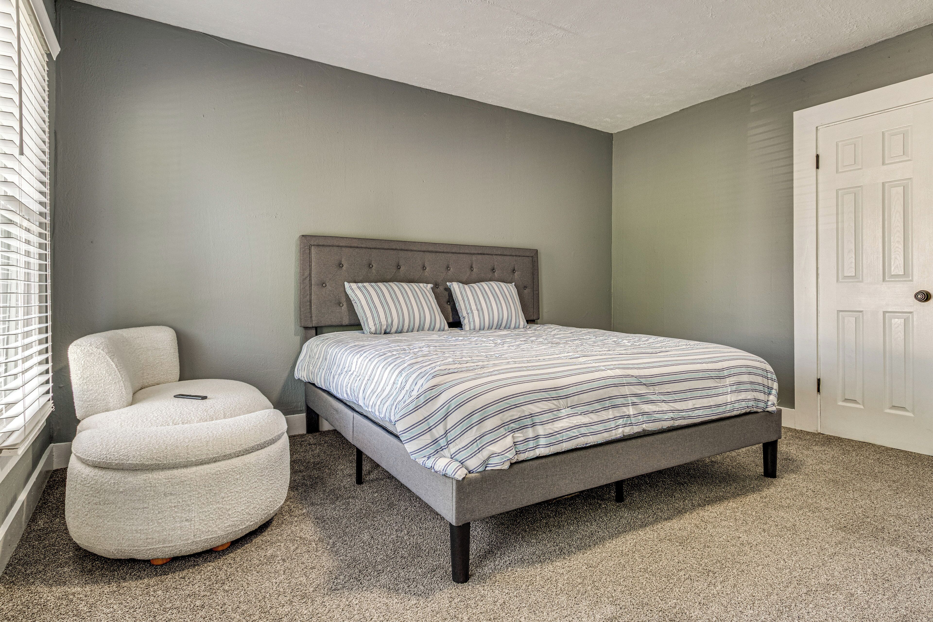 A bedroom with a bed, a chair, and a door.