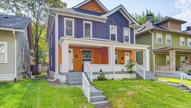 A two-story house with a front porch, a garage, and a small front yard. - Explore Downtown & Mass Ave! 3BR Indy Townhome (Indianapolis)