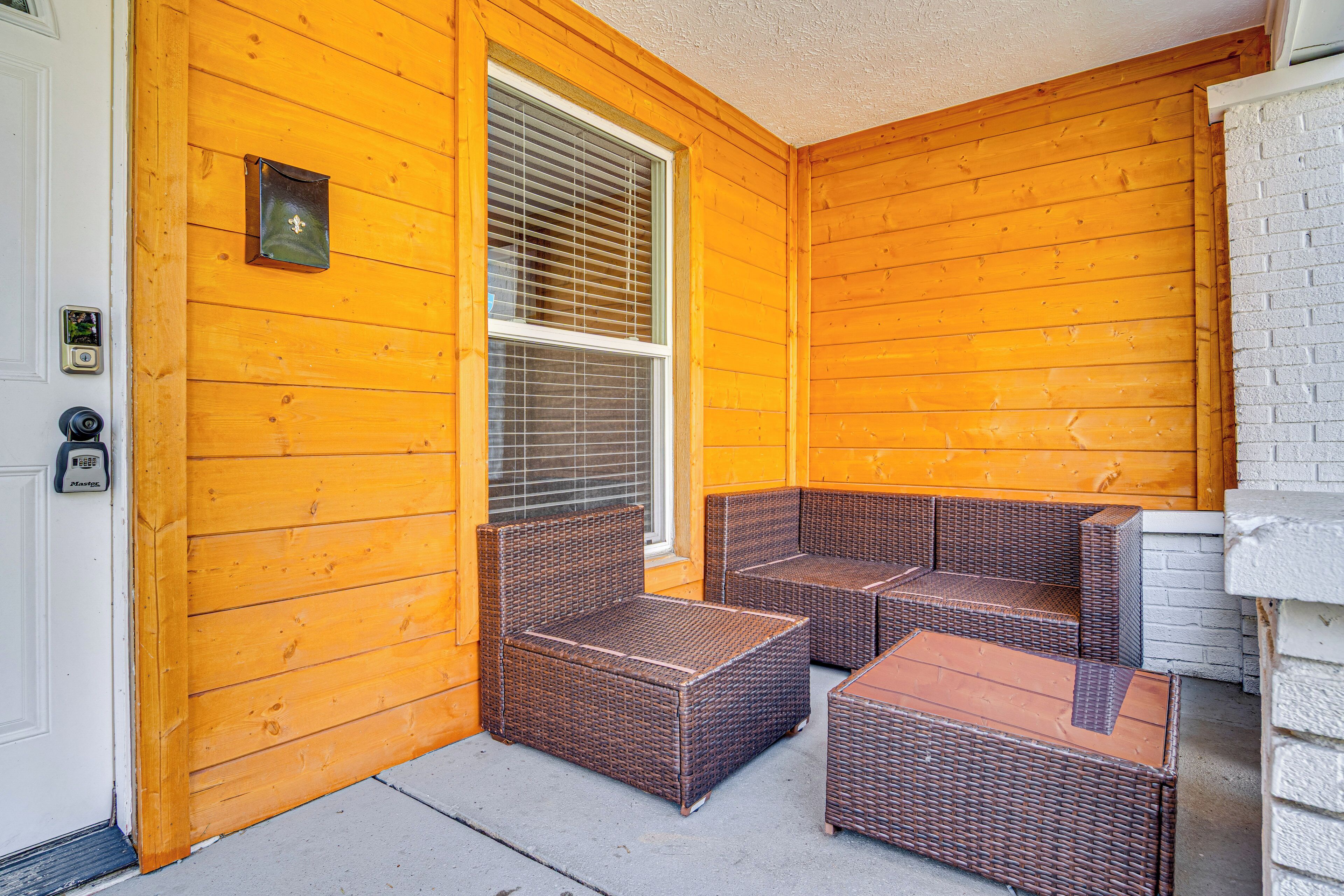A wooden porch with wicker furniture and a doorbell.