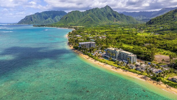 A coastal resort with beachfront villas, lush greenery, and mountainous backdrop. - Resort Condo on Oahu: Ocean & Pool Views! (Hau`ula)
