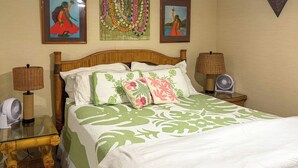 A neatly made bed with green and white bedding, two bedside tables with lamps, and two wall-mounted fans. - Resort Condo on Oahu: Ocean & Pool Views! (Hau`ula)