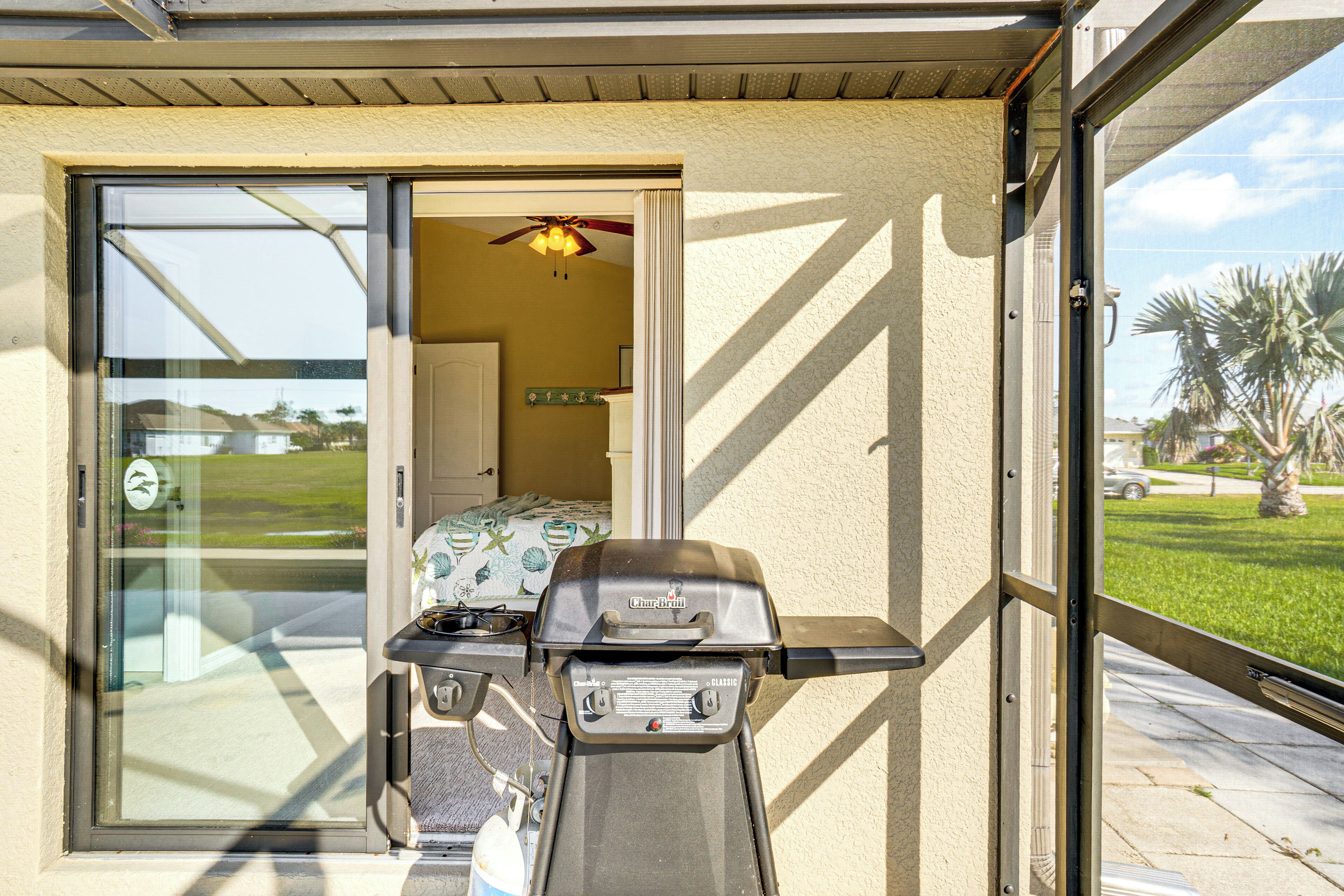 A glass door leading to a patio area with a grill and a ceiling fan.