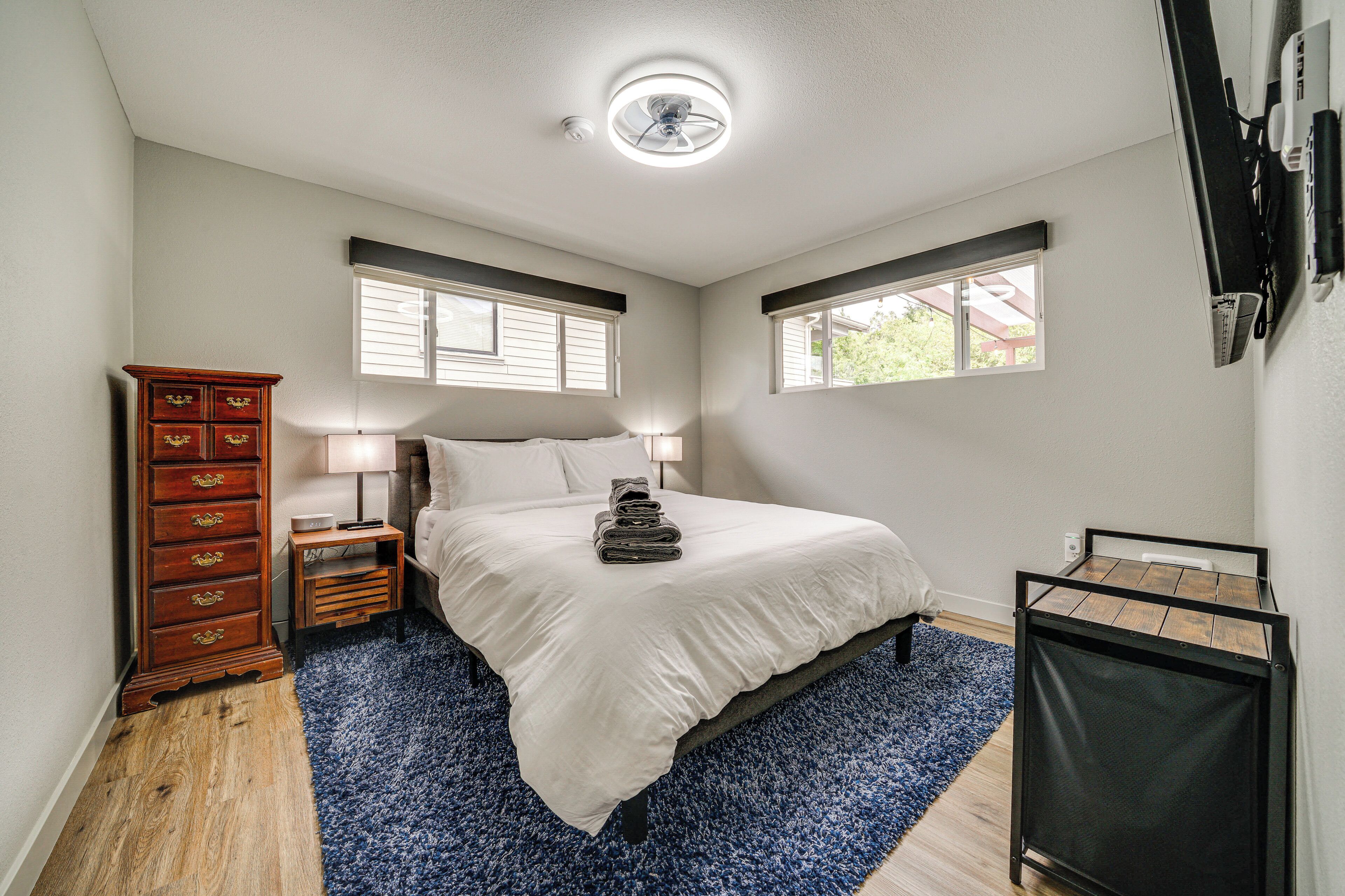 Een slaapkamer met een bed, een dressoir, een lamp en een raam.
