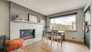 A living room with a fireplace, wooden flooring, and a dining area with chairs and a table. - 2 Blocks to Beach Park: Cozy Seattle Townhome (Seattle)
