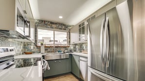 A modern kitchen with stainless steel appliances, grey cabinets, and a large window. - 2 Blocks to Beach Park: Cozy Seattle Townhome (Seattle)