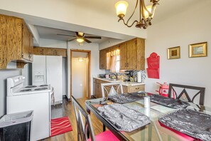Une cuisine compacte avec des meubles en bois, un réfrigérateur blanc, une cuisinière et un coin repas comprenant une table et des chaises en verre.