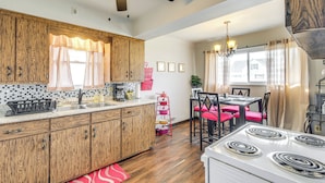 A kitchen with wooden cabinets, a white stove, and a dining area with red chairs. - 8 Mi to Dtwn Cleveland: Quiet Home w/ Fenced Yard (Garfield Heights)