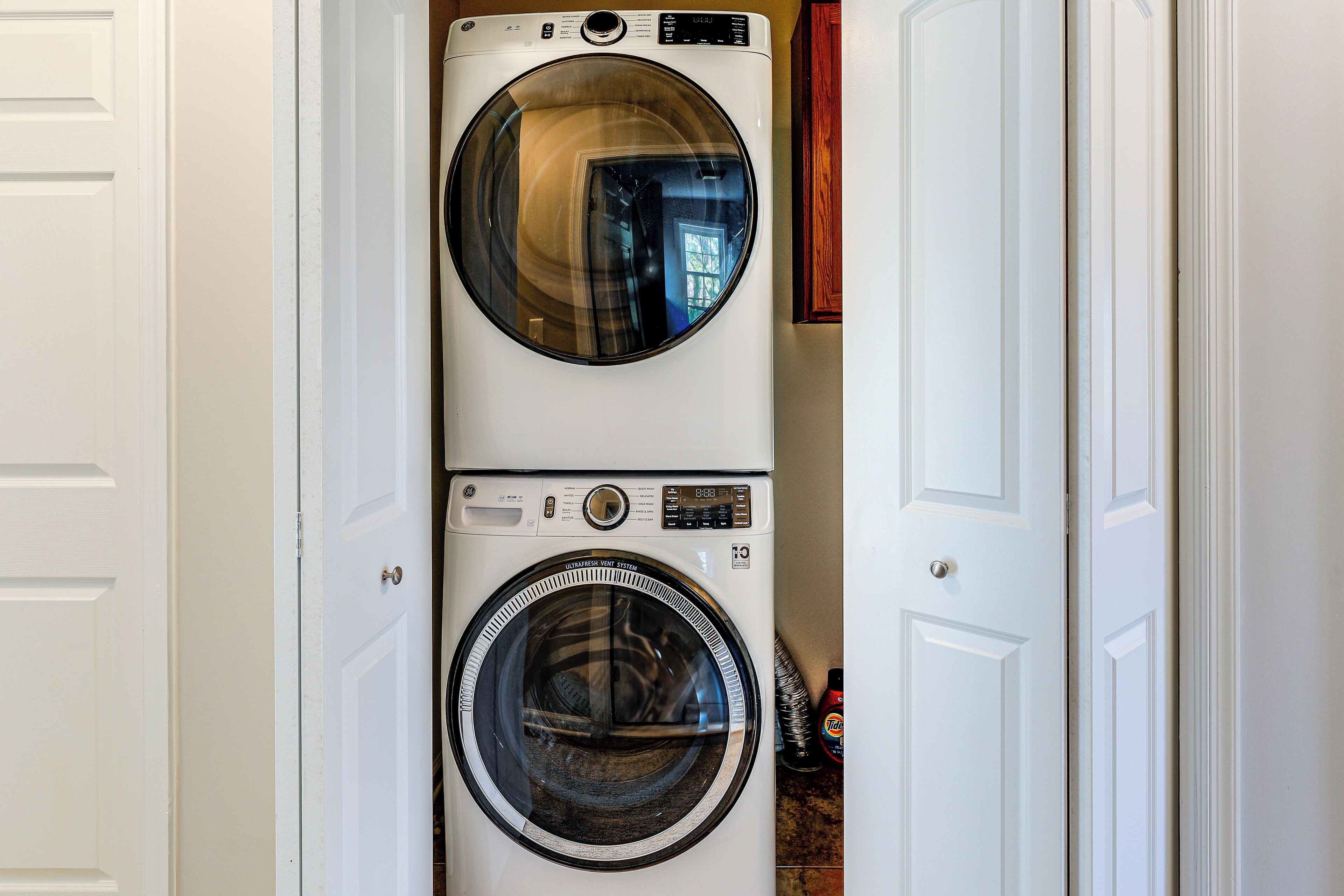 A front view of a stacked washer and dryer unit in a hallway.