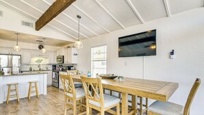 A spacious kitchen with wooden furniture, a large island, and a flat-screen TV mounted on the wall. - Walk to Beach: Ocean-view Home w/ Deck in Freeport (Freeport)