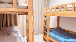 Duas camas beliche com estrutura de madeira e roupa de cama bege.