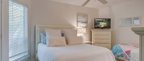 A bedroom with a bed, a dresser, a television, and a ceiling fan.