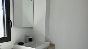 Une salle de bain avec un lavabo blanc, un miroir et un panier en osier.