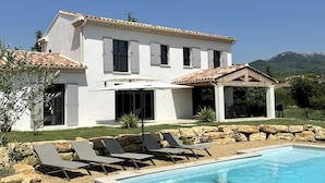 Une maison à deux étages avec une piscine, un espace salon extérieur et une vue sur les montagnes.