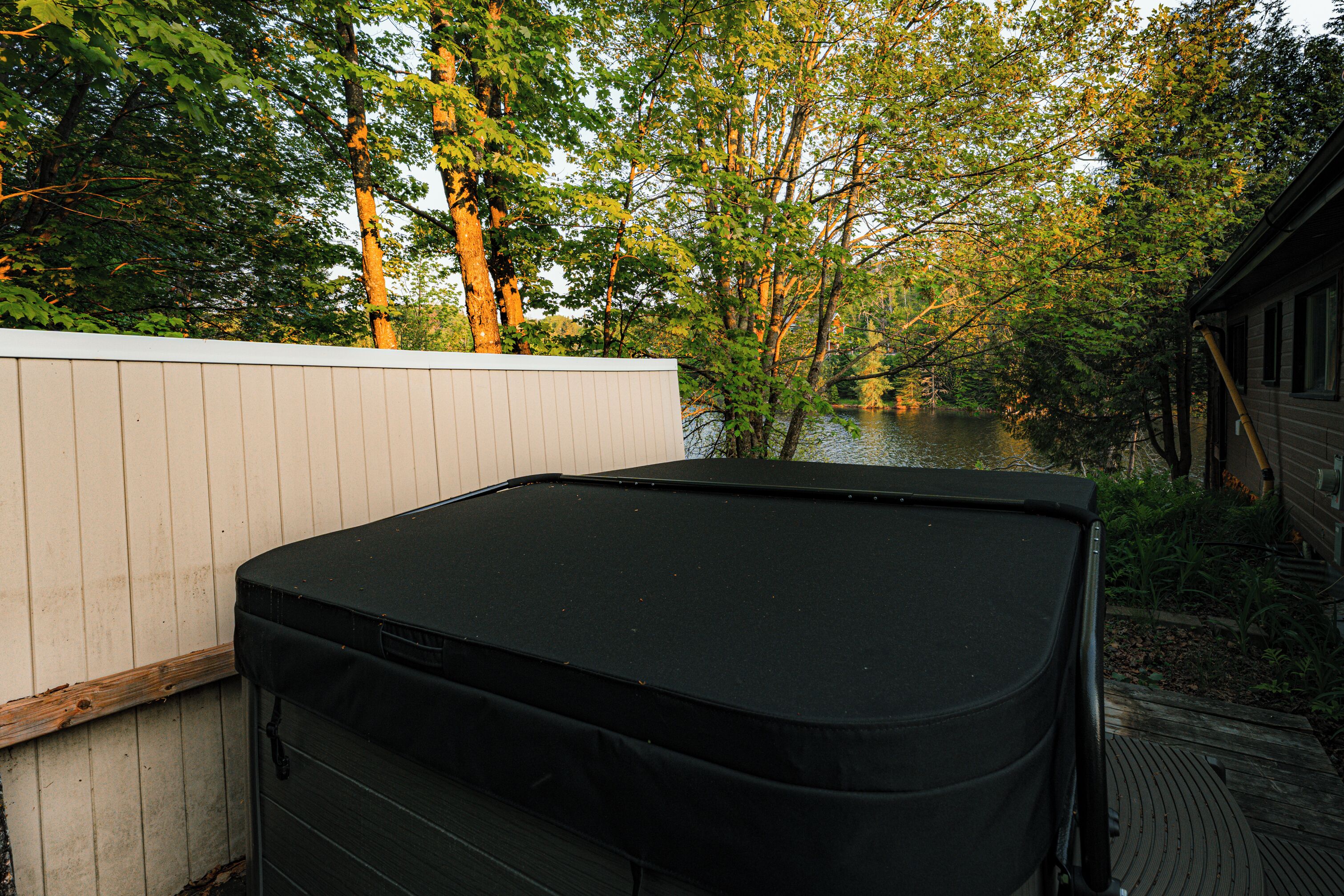 A black outdoor grill with a white fence and trees in the background.