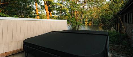 A black outdoor grill with a white fence and trees in the background.