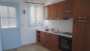 Une cuisine avec des meubles en bois, une cuisinière et une fenêtre avec des stores.