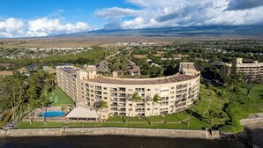 Un grande hotel a più piani con tetto curvo, piscina e vista sulla costa.