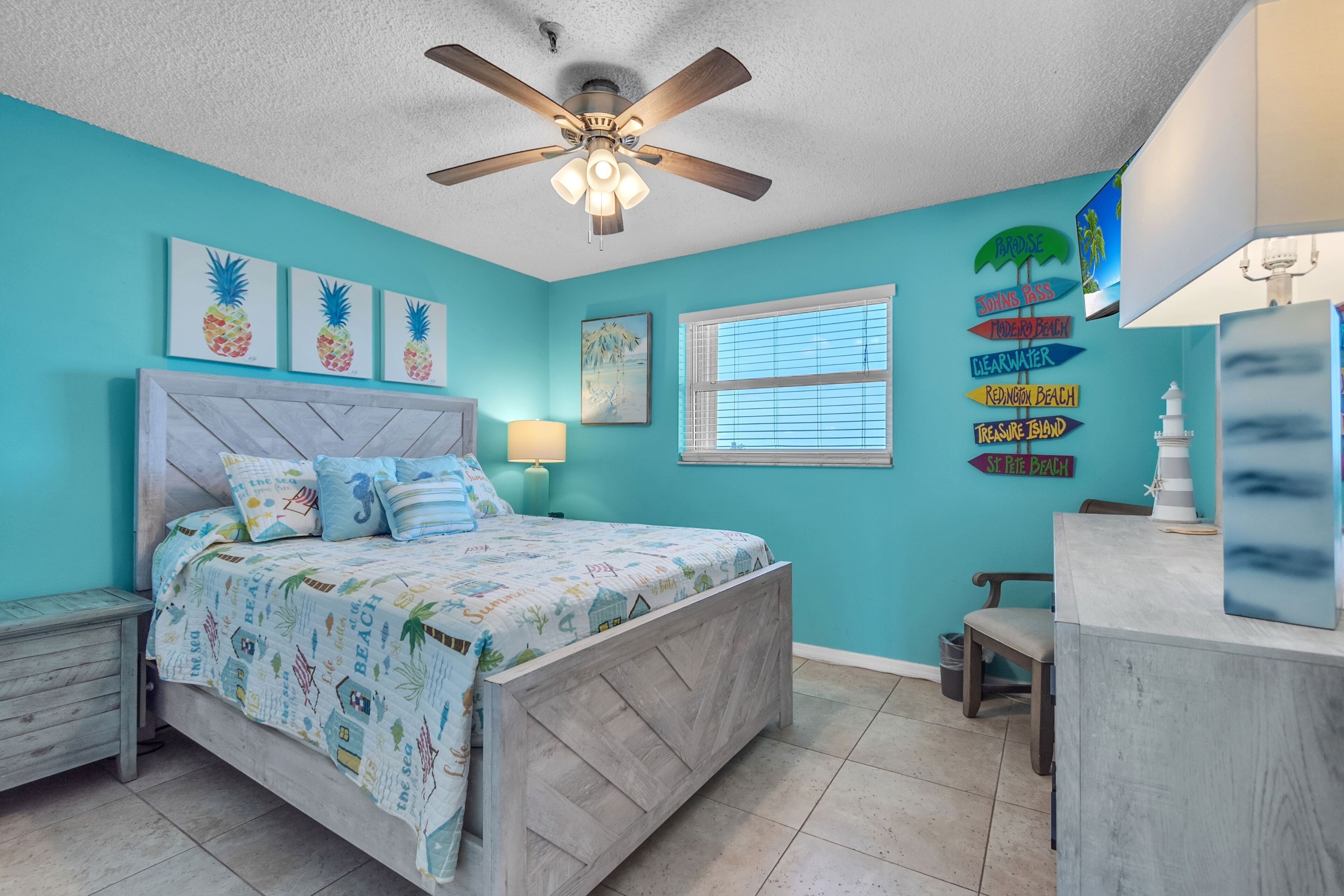 A bedroom with a bed, a ceiling fan, a window, and wall decorations.