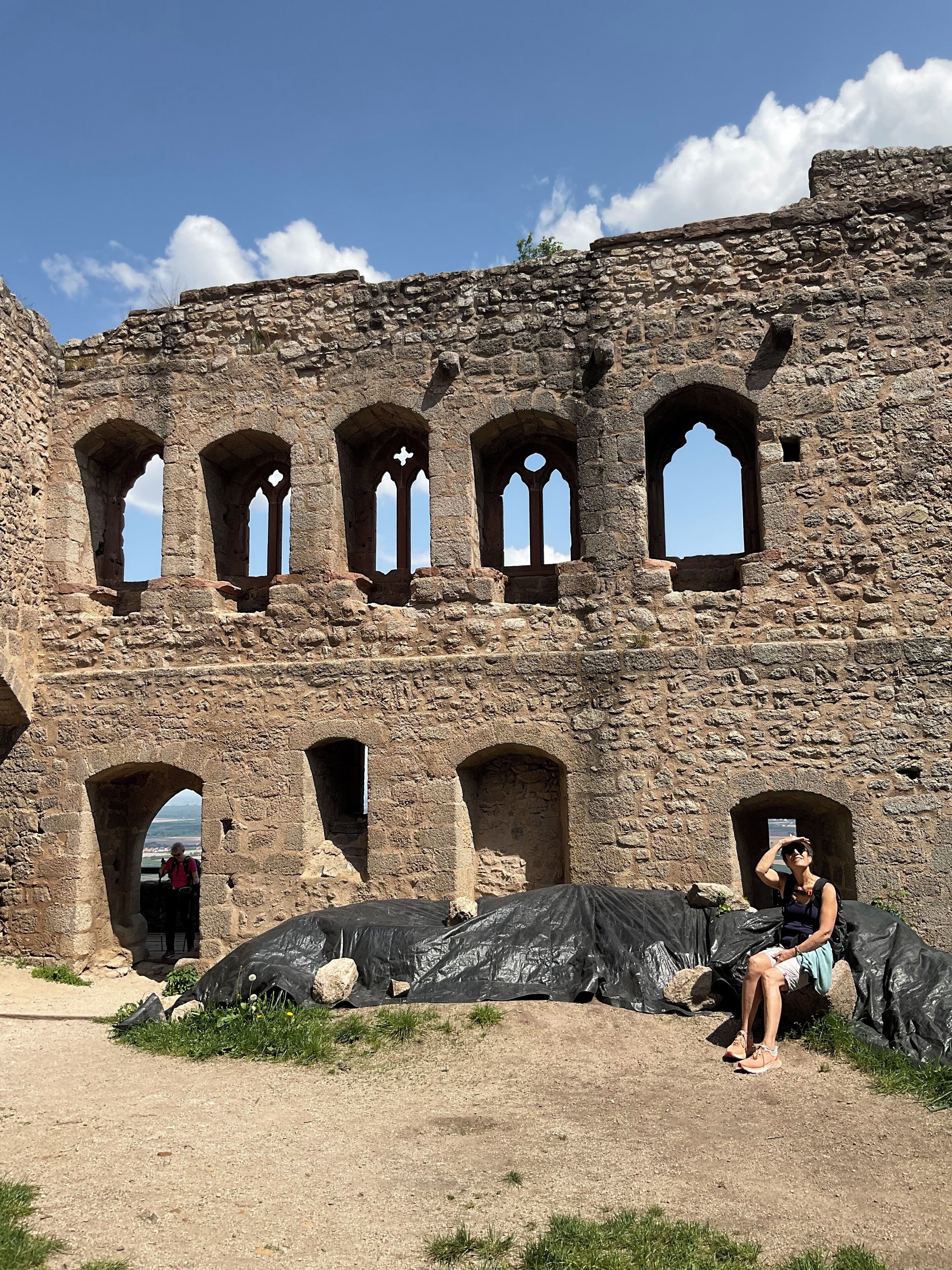 Ein historisches Steinhaus mit zahlreichen Rundbogenfenstern und einer Person, die sich in einem überdachten Bereich davor aufhält.