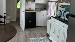 Una cocina compacta con armarios blancos, encimera negra y alfombra de estampado azul y blanco.