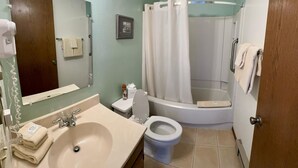 A bathroom with a sink, toilet, and bathtub. There is a towel rack with towels, a framed picture on the wall, and a shower curtain. - Unit 513 - Standard Condo (Winter Park)