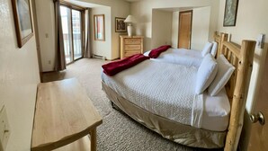 A bedroom with a large bed, wooden headboard, a wooden dresser, a desk, and a window with curtains. - Unit 521 - Standard Condo (Winter Park)