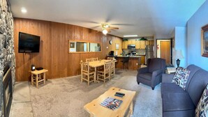 A living room with a wooden dining table, a gray sofa, and a ceiling fan. - Unit 521 - Standard Condo (Winter Park)