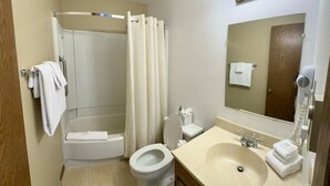 A bathroom with a shower, toilet, sink, and a mirror with lights. - Unit 521 - Standard Condo (Winter Park)