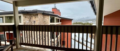 A wooden deck with a stone wall and a view of a snowy mountain range.