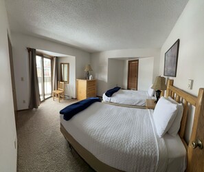 A hotel room with two beds, a wooden dresser, a chair, a desk, and a large window with curtains. - Unit 531 - Standard Condo (Winter Park)
