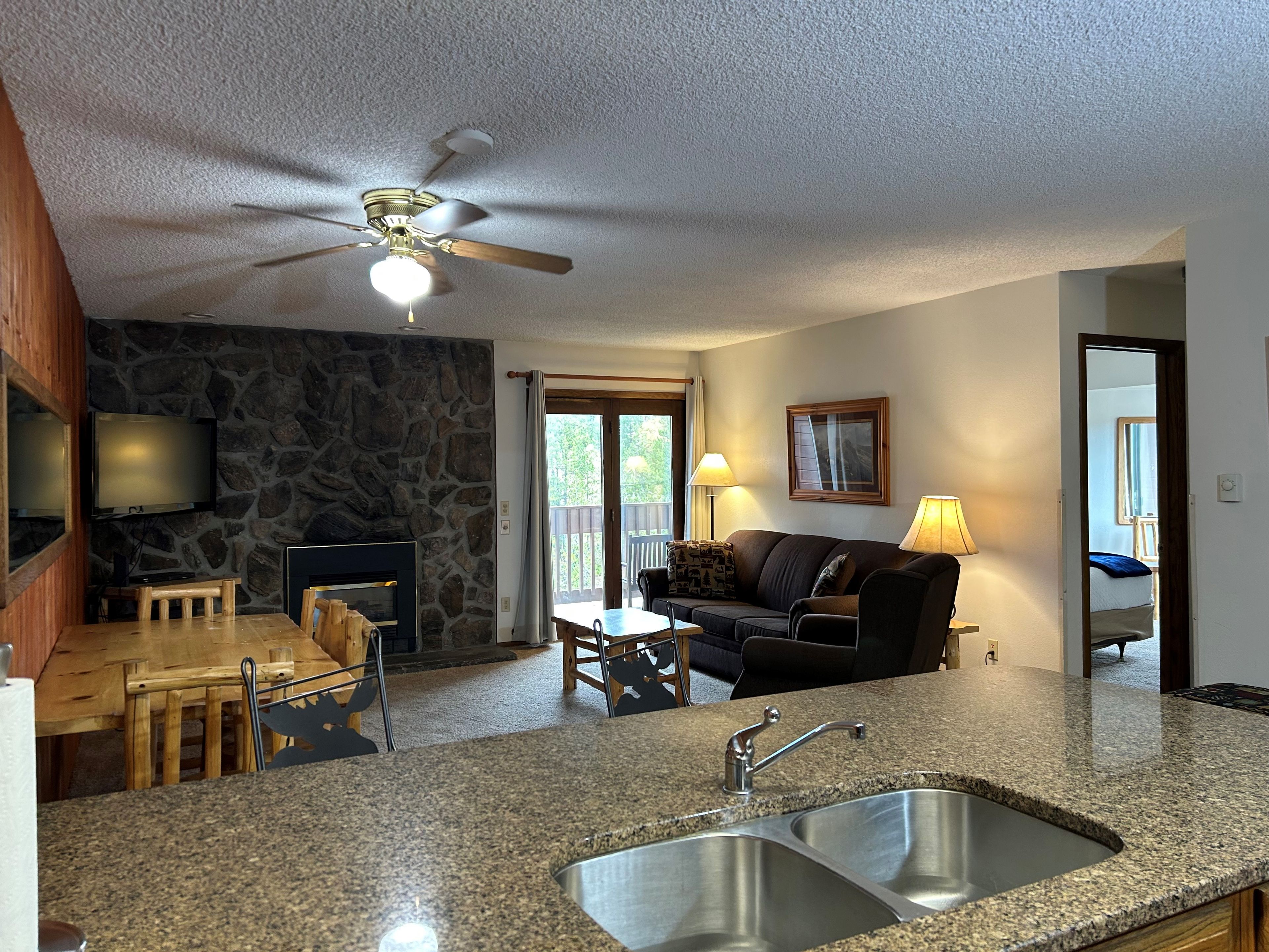 A kitchen with granite countertops, a double sink, and a ceiling fan.