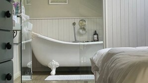 A modern bedroom with a large bathtub, a bed, and a dresser. - Kalk Bay Condo at The Majestic (Cape Town)