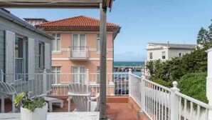 A balcony with a view of the sea, a white railing, and a potted plant. - Kalk Bay Condo at The Majestic (Cape Town)
