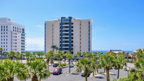 A high-rise hotel with a central atrium, parking lot, and palm trees. - 3rd Floor Condo w/ Large Community Pool in Central Destin! 🌺🐬 (Destin)