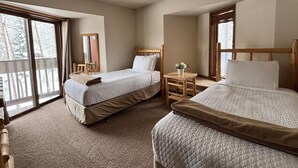 A hotel room with two beds, a small table, a chair, a mirror, and large windows with a view of trees. - Unit 624 - Updated Condo (Winter Park)