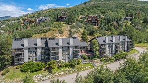 A multi-story hotel with balconies, set in a mountainous area with lush greenery.