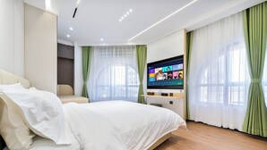 A modern hotel room with a large bed, a flat-screen TV, and green curtains. - MUDONG YOUTH  HOSTEL (Harbin)
