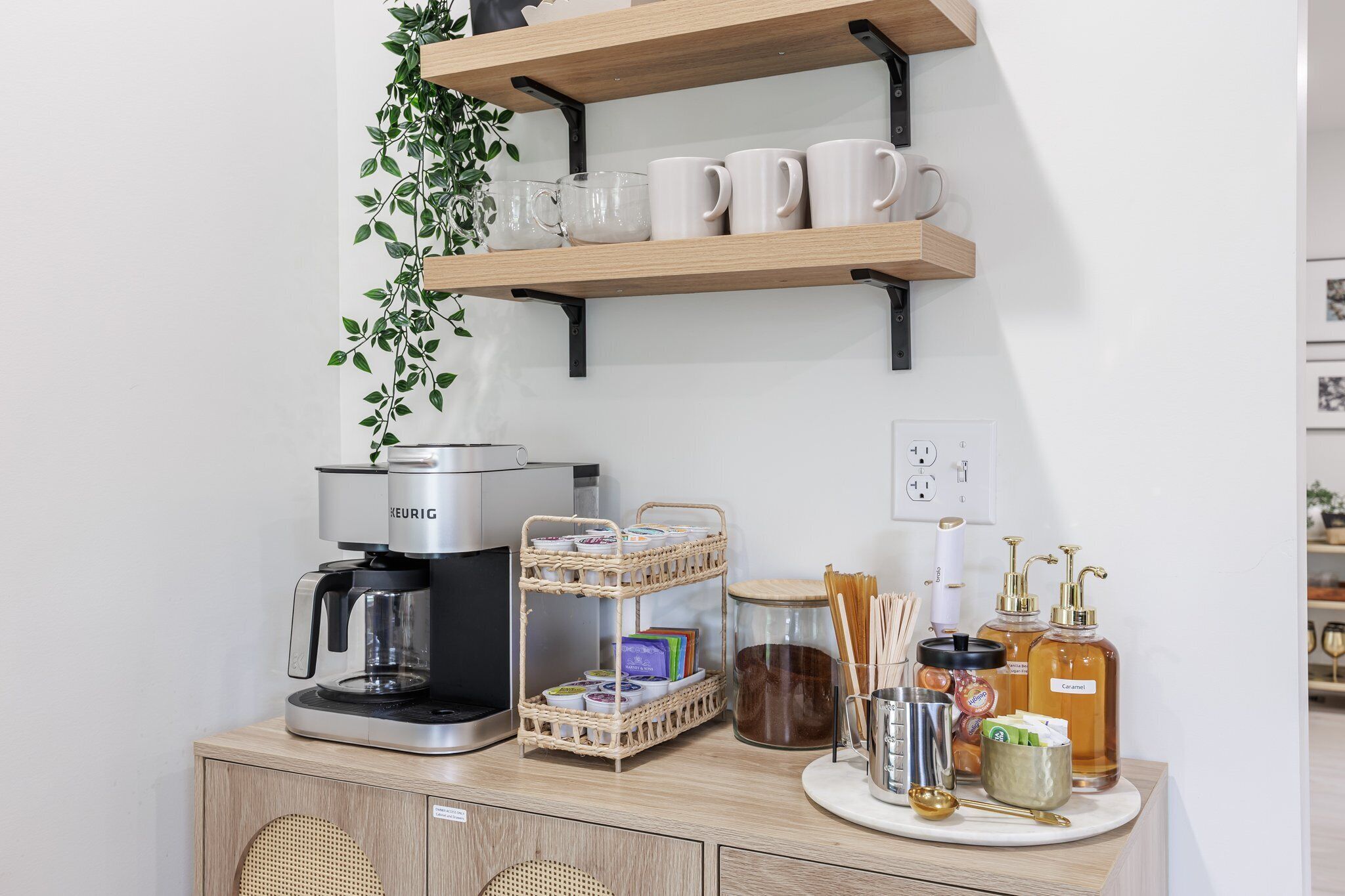 A kitchenette with a coffee maker, a wicker basket, and various kitchen items on a wooden counter.